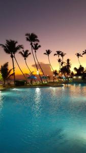 una piscina de agua con palmeras y una puesta de sol en Beachfront, Juandolio, en Juan Dolio