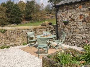 a patio with a table and chairs and a stone wall at Fletchers Barn in Alderwasley