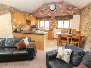 a kitchen and living room with a couch and a table at Fletchers Barn in Alderwasley