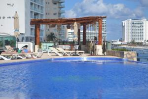 a large blue swimming pool with a pergola and chairs at Ocean View Condo in Cancún