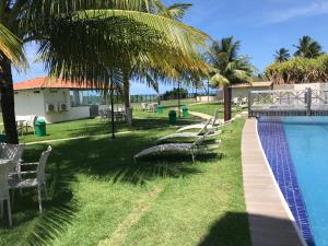 a swimming pool with chairs and a house and palm trees at MAUÍ BEACH RESIDENCE - Beira-mar Tamandaré- Próximo a Igreja de São Pedro- PE in Tamandaré