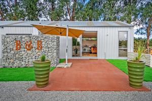 a house with an umbrella in front of a building at Farm Retreat B&B in West Melton