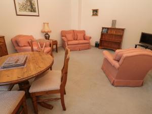 a living room with orange furniture and a table and chairs at Ivy Cottage in Wooler