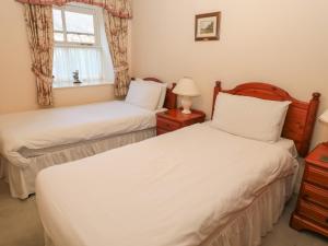 two twin beds in a room with a window at Ivy Cottage in Wooler