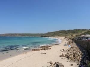 a beach with people on the sand and the ocean at Forge Cottage in Sennen