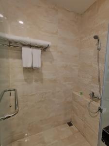 a bathroom with a shower and a toilet and towels at Grand Samota Hotel in Sumbawa Besar