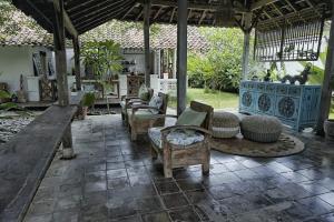 un patio con un montón de sillas y mesas en Wooden house at Semadi living en Sukawati