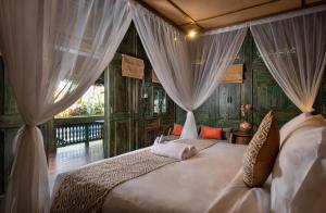 a bedroom with a bed with drapes at Kutus Kutus Estuary Saba Beach in Saba