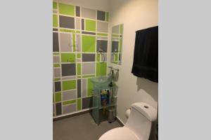 un bagno con piastrelle verdi e grigie sul muro di Departamento en Edificio El Semillero a Monterrey Altre 18 foto