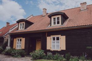 uma casa castanha com um telhado vermelho em Šaha Kluba Apartamenti em Kuldīga