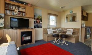 uma sala de estar com uma televisão, uma mesa e uma lareira em The Wavering Knave em Starcross