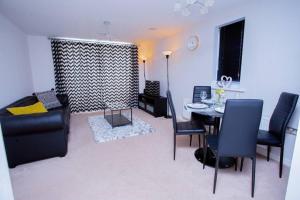 uma sala de estar com um sofá, uma mesa e cadeiras em Mills Apartment - Two bedroom en-suite apartment em Northampton