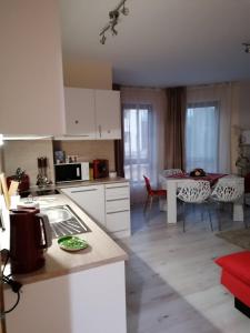 cocina con armarios blancos, mesa y comedor en By the Waves luxury beach apartment en Varna