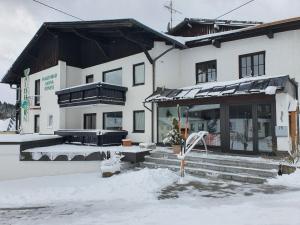 un bâtiment recouvert de neige avec un banc devant lui dans l'établissement HOTEL WALDHORN, à Jungholz