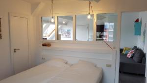 Schlafzimmer mit einem weißen Bett und einem Spiegel in der Unterkunft Le Chanteclair in Gembloux