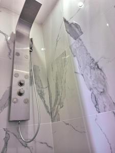 a shower in a bathroom with a marble wall at Les Suites Fénelon in Le Cateau