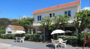 a building with tables and umbrellas in front of it at Hôtel Au Bon Landais in Biscarrosse-Plage