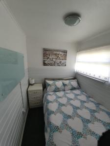 a small bedroom with a bed and a window at Chalet 66 in Skegness
