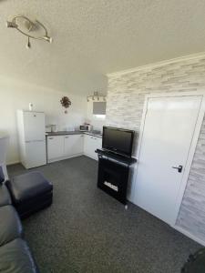 a living room with a couch and a tv and a kitchen at Chalet 66 in Skegness