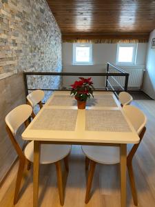 a wooden table with chairs and a vase with red flowers at Penzion U Martina in Mariánské Lázně