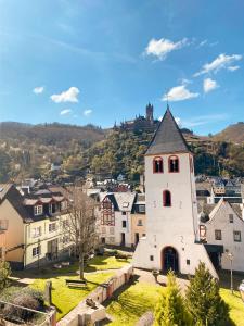 a small white building with a tower in a village at Haus Mosel Tales in Cochem für bis zu 9 Personen in Cochem