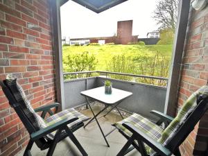 un patio con 2 sillas y una mesa en el balcón en Strandkorb, en Horumersiel