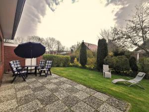 une terrasse avec une table, des chaises et un parasol dans l'établissement Sandstrand, à Wangerland