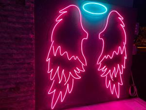 a neon sign with two angel wings on a wall at Blue Star Apartments in Ulcinj