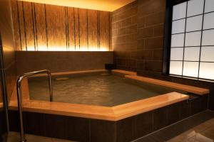a jacuzzi tub in a brown tiled bathroom at Almont Hotel Nippori in Tokyo