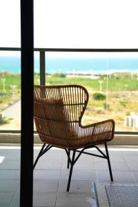 un banco de mimbre sentado frente a una ventana en 4 Bedroom Beach Apartment with Stunning Views en Nahariyya