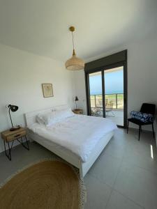 Habitación blanca con cama y balcón. en 4 Bedroom Beach Apartment with Stunning Views en Nahariyya