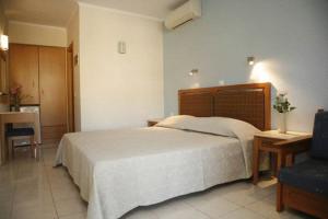 a bedroom with a large bed and a blue chair at Akti Damnoni in Damnoni