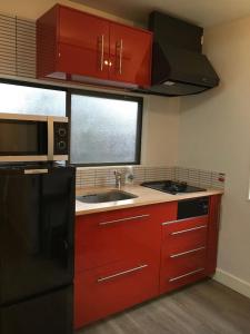 a kitchen with red cabinets and a black refrigerator at Iida Accommodation in Iida
