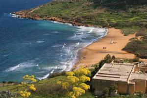 una spiaggia con un edificio e l'oceano di Spacious apartment in Marsalforn, Gozo a Marsalforn