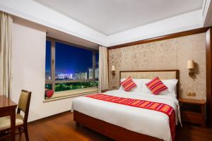 a bedroom with a bed and a desk and a window at Sanya Seacube Holiday Hotel in Sanya