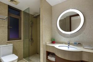 uma casa de banho com um WC, um lavatório e um espelho. em Sanya Seacube Holiday Hotel em Sanya