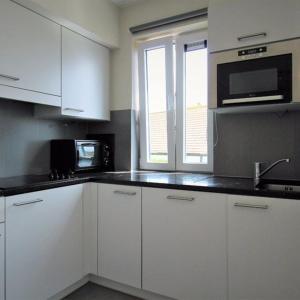 a kitchen with white cabinets and a black counter top at Duplex met zwembad Neoportus in Nieuwpoort