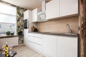 a kitchen with white cabinets and a table at Beach Break Deco & Sleeping in Katwijk aan Zee