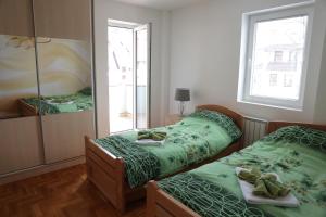 una camera con 2 letti con lenzuola verdi e specchio di Apartman Rastko a Nova Varoš