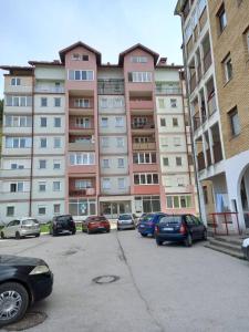a parking lot with cars parked in front of a building at Apartman Rastko in Nova Varoš