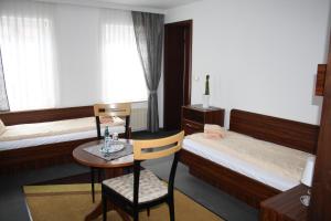 a room with two beds and a table with a chair at Hotel & Restaurant Aragwi in Salzwedel