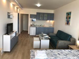 a living room with a couch and a kitchen at Студио Сънрайз А28, Лозенец in Lozenets