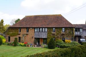a large brick house with a green yard at Finchden Barn in Tenterden