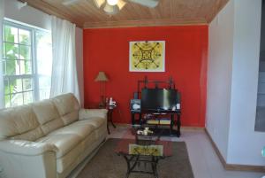 a living room with a couch and a red wall at Sapphire Garden Townhouses in Georgetown