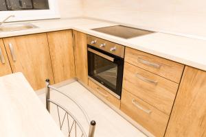 cocina con armarios de madera, fregadero y fogones en Urban Retreat Luxury HideAway en Oradea