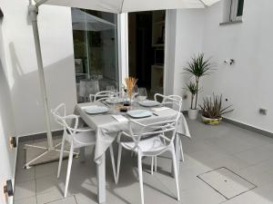 a white table with white chairs and an umbrella at Villa Luminosa in Torre del Lago Puccini