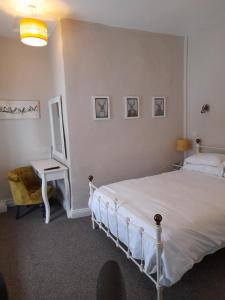 een slaapkamer met een wit bed en een bureau bij The Raven Inn in Ruthin