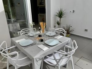 a dining room table with white chairs and a gray table cloth at Villa Luminosa in Torre del Lago Puccini