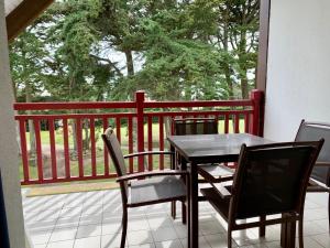 un tavolo e sedie in legno su un balcone con vista sugli alberi di Appartement dans résidence de standing avec terrasse et vue mer a Le Pouliguen