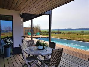a wooden deck with a table and chairs and a pool at B&B La Chabetaine in Morhet